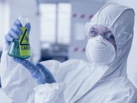 Scientist in protective suit with hazardous chemical in flask
